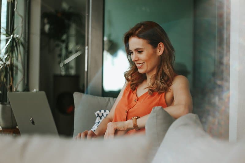 a female marketing VA working on a laptop and smiling at her screen