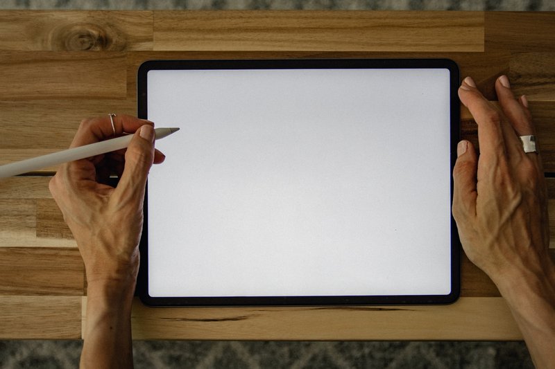 womans hands holding a blank ipad and digital pen which can help with using free marketing tools