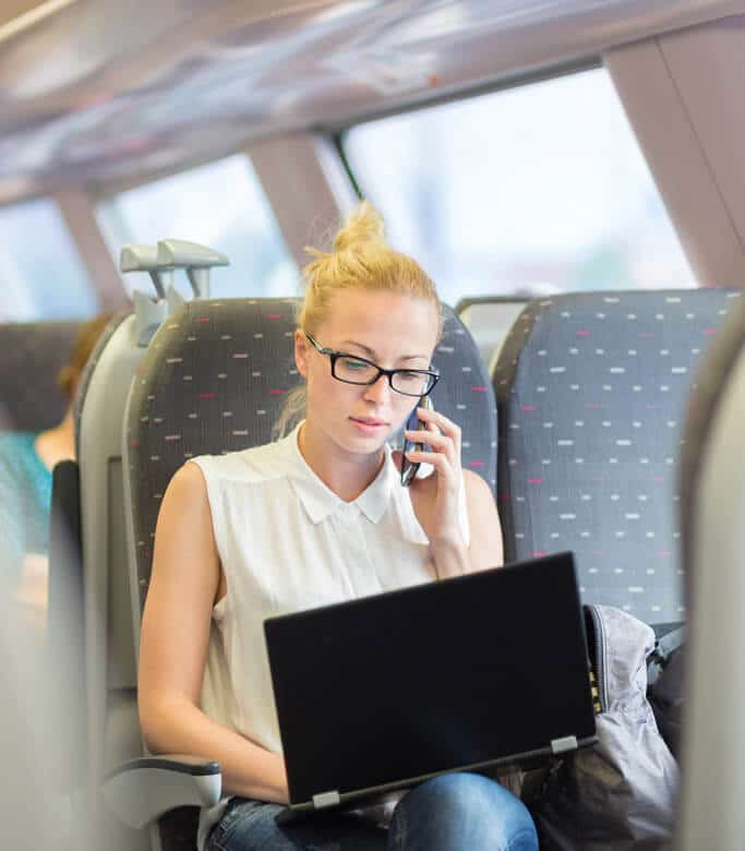 Woman with mobile phone on a train with her laptop
