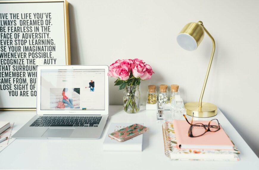 Image of a clean and tidy desk with lamp, laptop, phone, a print nad some roses