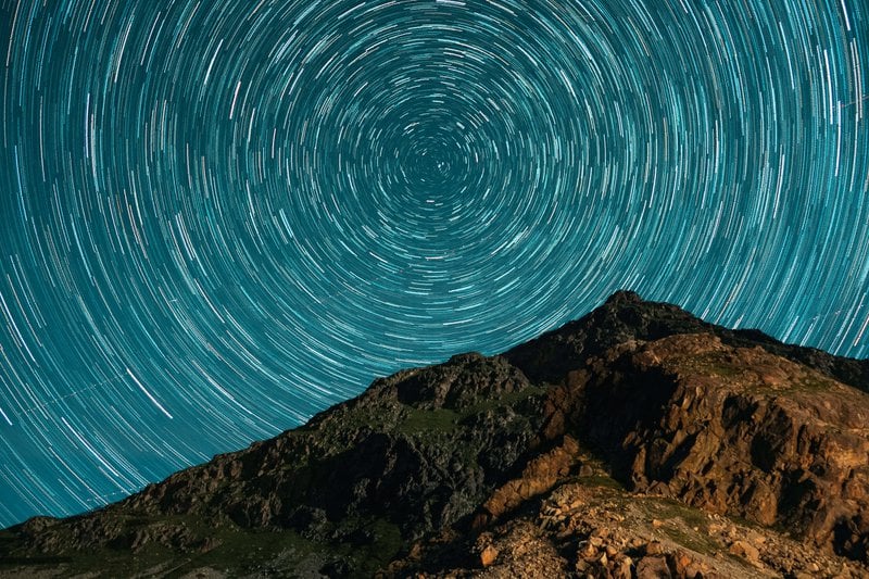 a mountain with a star trail in the sky
